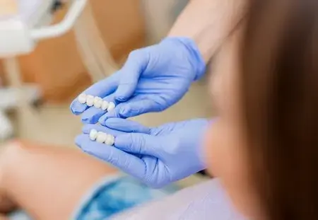 Dental Crowns in Montville, NJ That Protect and Restore Your Teeth Dental professional compares tooth-colored crown samples beside a patient in Montville, NJ