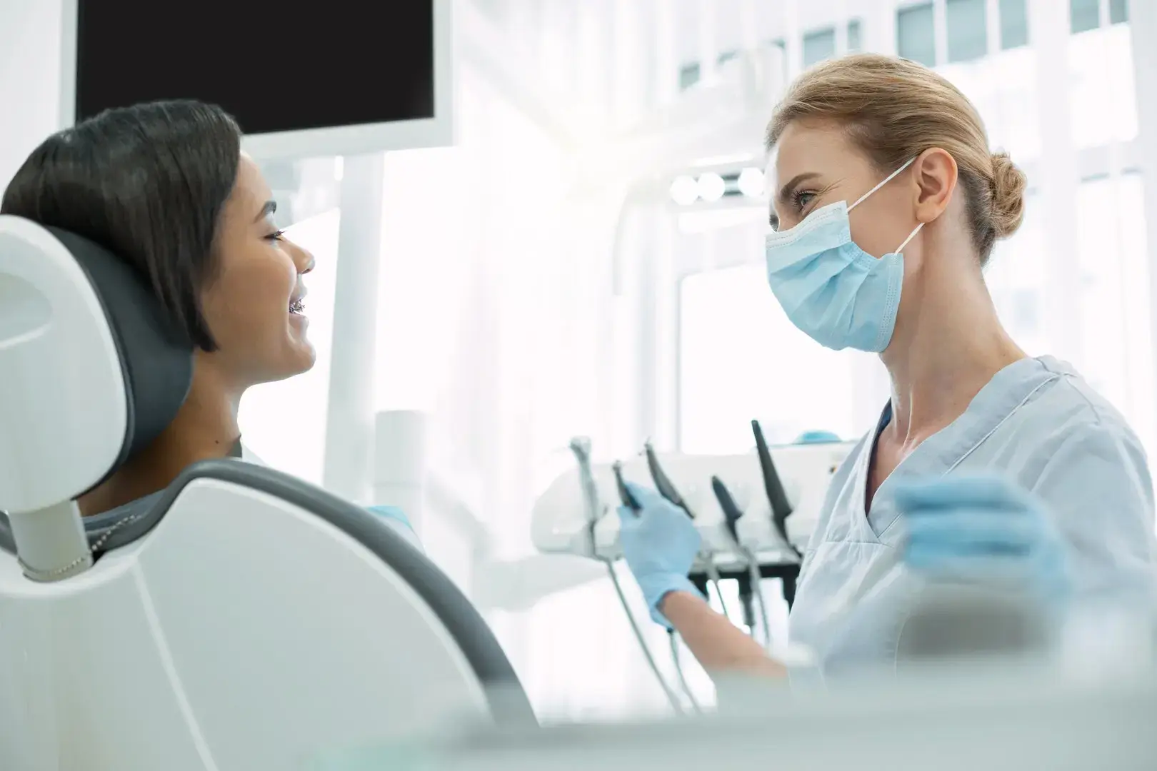 Masked dental professional talks with a patient in a Montville, NJ dental office
