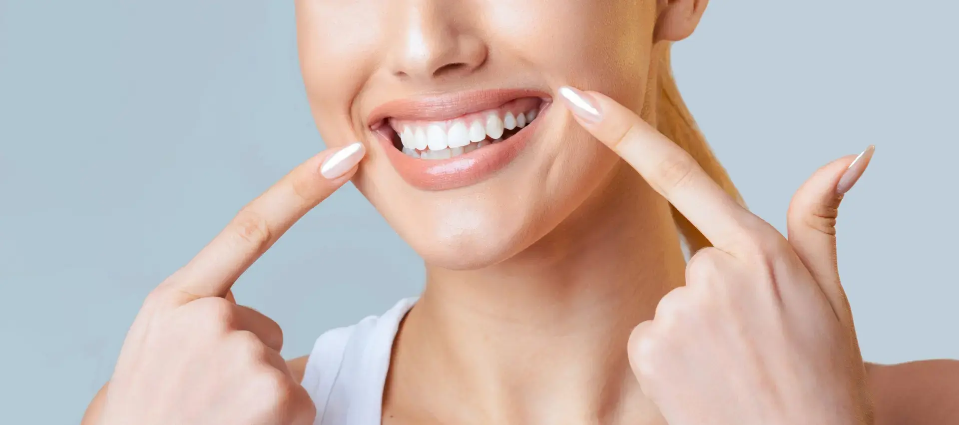 Smiling woman points to her teeth, highlighting cosmetic dentistry in Montville, NJ