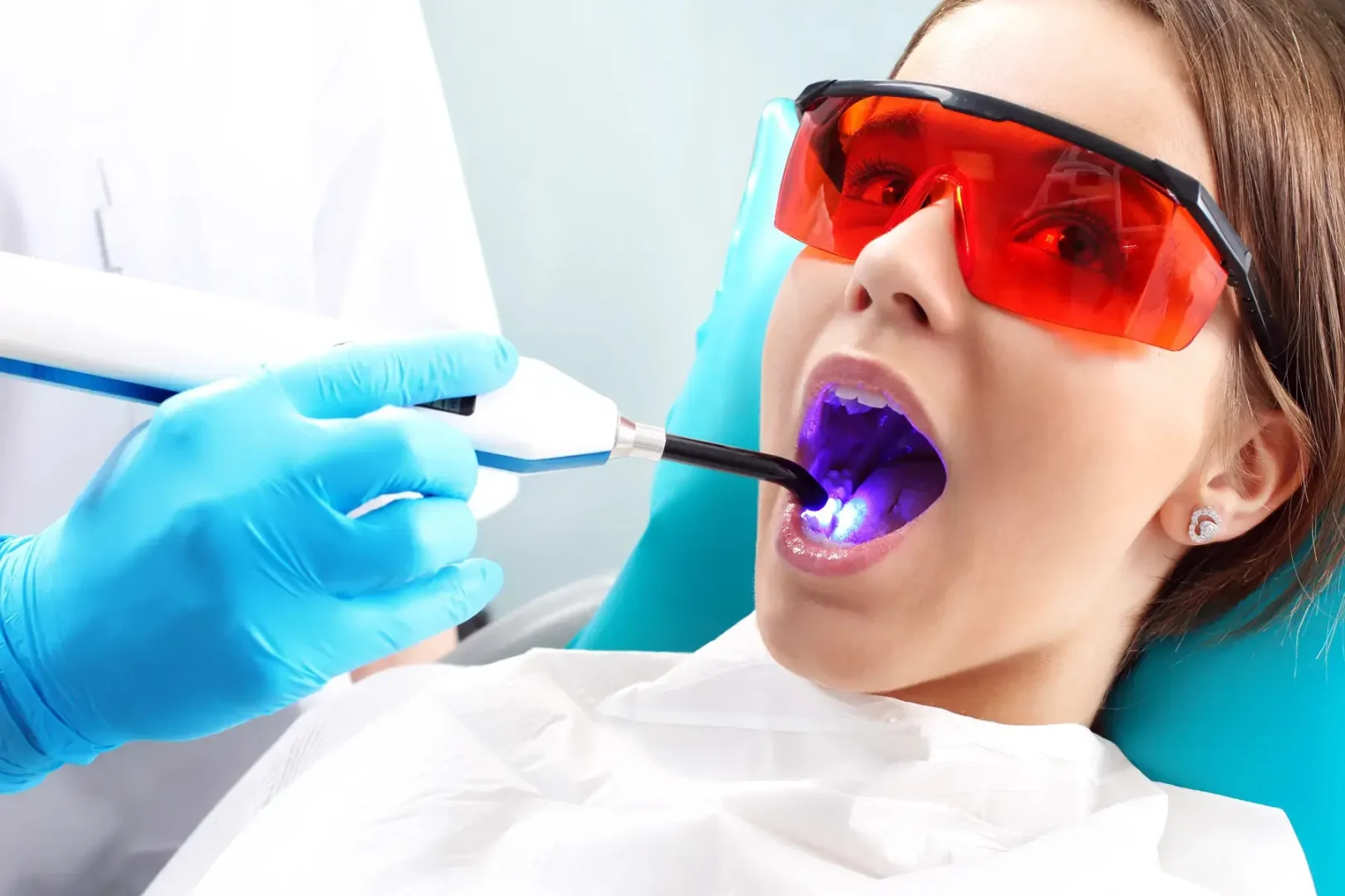 Dental professional uses a curing light on a patient wearing protective glasses in Montville, NJ